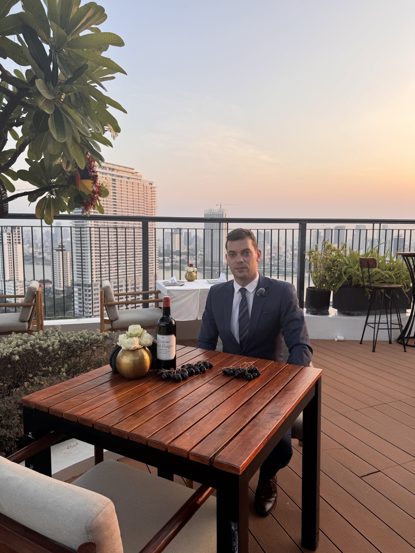 A Red Raven founder at a Phnom Penh rooftop sunset with a Bordeaux table setting